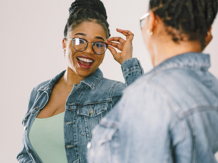 Woman in glasses smiling at her reflection